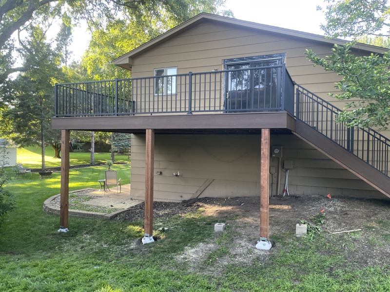 Elevated composite deck with stairs and black railings at a residential home in Andover, MN