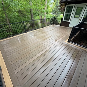 Finished custom composite deck installation surrounded by mature trees in Ramsey, MN