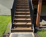 Composite deck stairs with black aluminum railings and custom paver landing in Brooklyn Park, MN